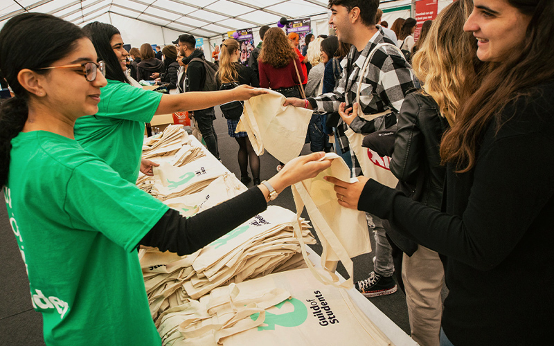 a student staff member giving out tote bags