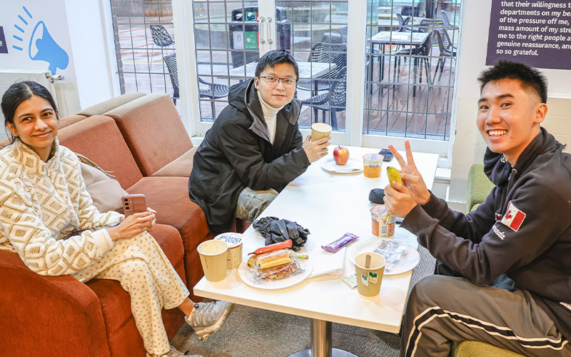 a photo of students with breakfast items on a table smiling at the camera